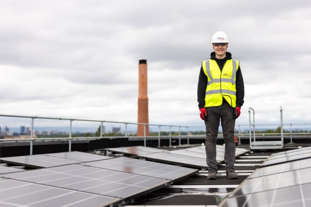 Technicien sur la toiture d'un bâtiment industriel équipé de panneaux photovoltaïques