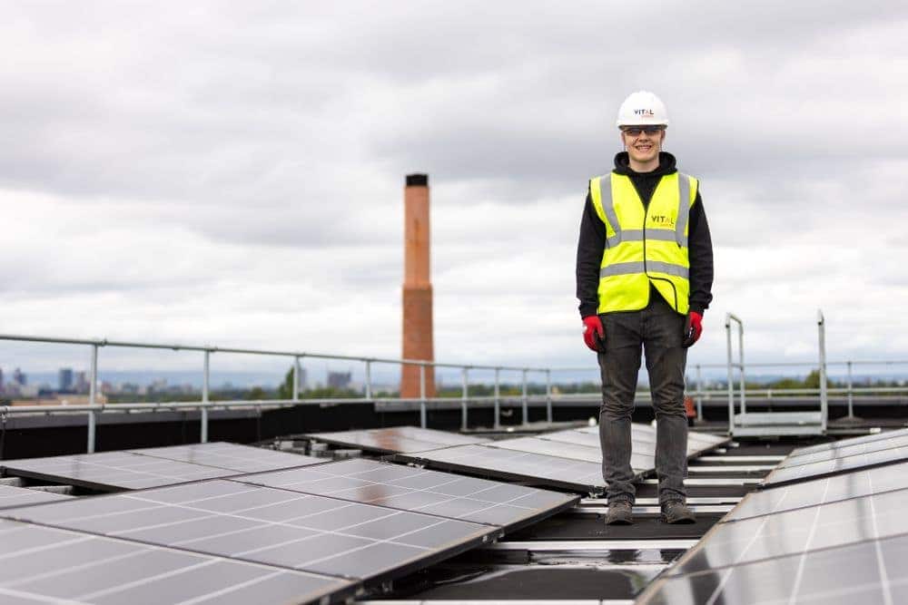 Technicien sur la toiture d'un bâtiment industriel équipé de panneaux photovoltaïques